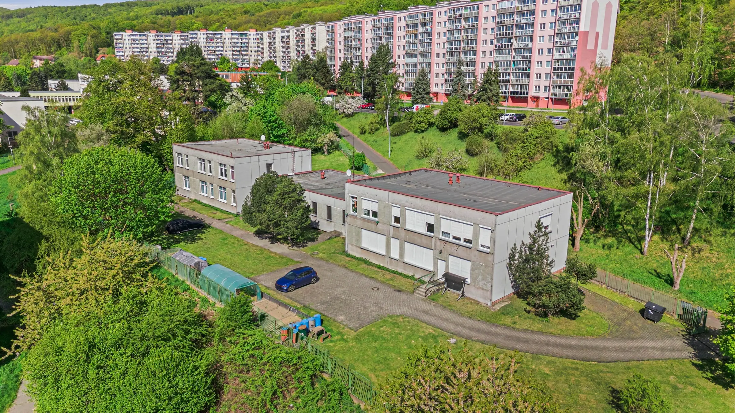 Areál ubytovny Beta House v Litvínově-Janově z dronu, parkoviště před budovou a v pozadí panelové domy a zalesněný svah